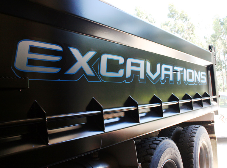 Elite Excavations tip truck, blue and grey vinyl lettering on the black bin